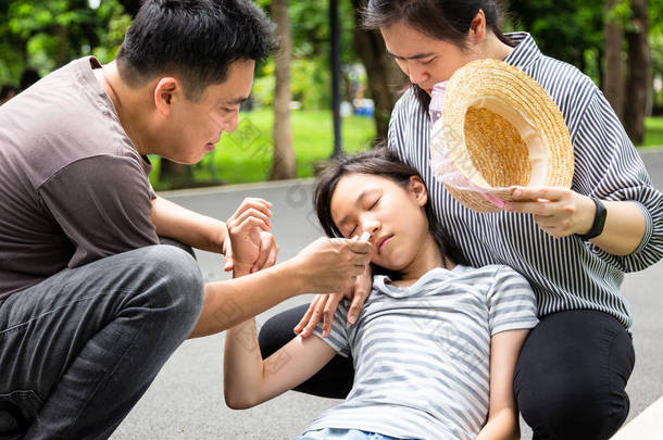 亚洲<strong>小孩</strong>，有中暑、高烧、眩晕、头晕、晴天生病的女儿、可爱的女孩，夏天在室外晒黑时筋疲力尽，感到头晕，爸爸妈妈 