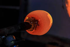 玻璃鼓风机在一根玻璃制造商车间的窑中加热，在杆上加热熔化玻璃的气泡