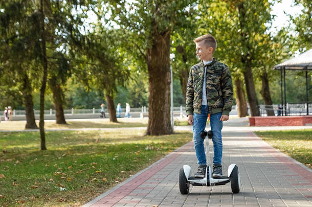 一个男孩在公园里骑着气垫板，一个自平衡的滑板车。积极的生活方式技术未来