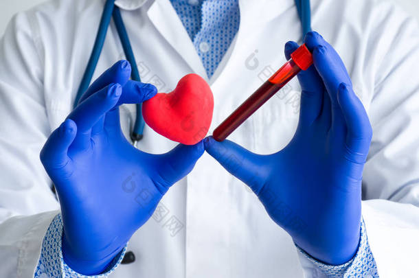 实验室医疗诊断，心脏和心血管概念照片检测。 医生或实验室技术人员一只手拿着装有血液的实验室试管，另一只手拿着心形试管