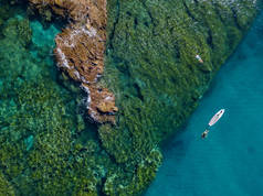 在空中看到水面上有一块桨板漂浮在透明的海面上，在浮潜。 在海上洗澡。 意大利卡拉布里亚Tropea 。 潜水、放松和暑假。 意大利海岸、海滩和岩石.