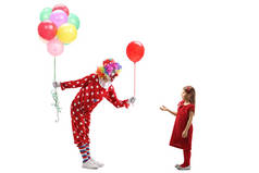 小丑拿着一堆气球把一个红色的气球给了一个小 