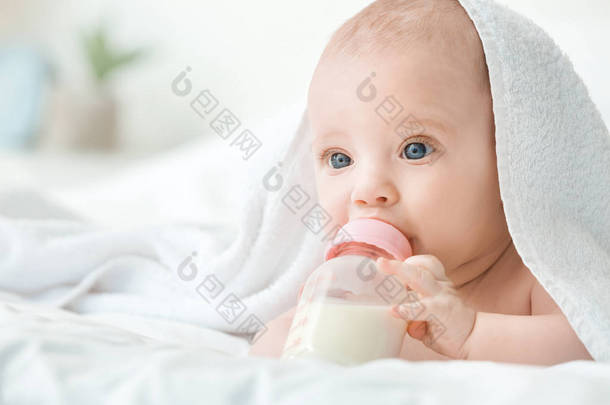 可爱的小宝宝躺在床上喝牛奶的肖像