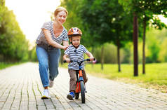 幸福的家庭母亲教孩子儿子骑自行车在公园