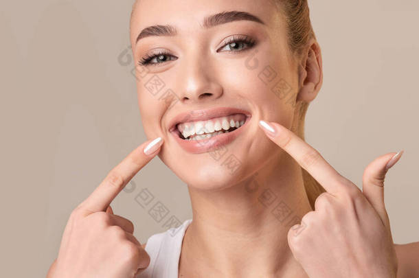 Young Woman Touching Mouth Smiling To Camera On Beige Background