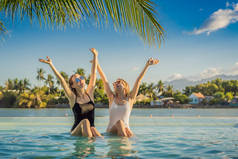 暑假期间，两个漂亮的年轻女子坐在一个度假胜地游泳池边。缔约方、热带国家的旅游业