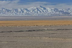 从Nnal.Highway G315俯瞰沙漠柴达木盆地到早上昆仑山东奇曼塔格山脉的雪峰。海西县-青海省-中国