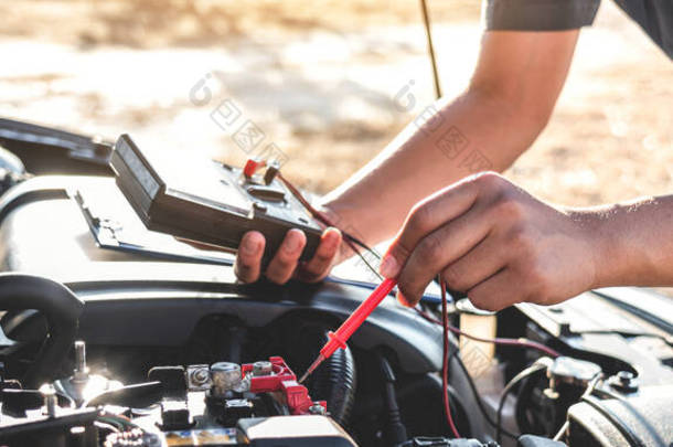 机械修理工检查发动机汽车在汽车维修服务中的应用，用数字万用表测试电池测量各种值并进行分析.