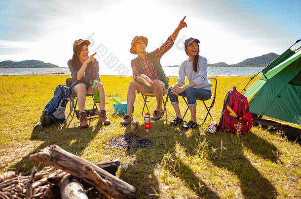 在秋天的林间小径上搭起一个户外帐篷后，一群亚洲登山者正坐在那里享受着喝一杯的乐趣。远足、远足、团队、森林、露营、活动概念.
