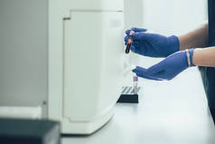 专业实验室的血液分析仪小心地放置试管，双手戴橡胶手套的剪影