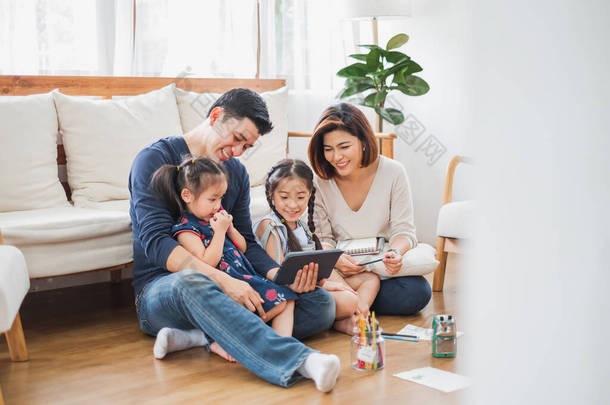 快乐的亚洲家庭使用平板电脑、笔记本电脑来玩游戏、放松家里的生活习惯