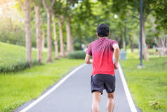 年轻的成年男子穿着运动服在公园里跑来跑去，跑步的男子在路上慢跑，亚洲运动员在早上散步和锻炼。健康、健康、健康的生活方式和锻炼理念