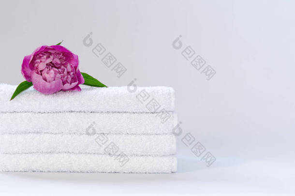 四个白色整齐折叠的毛巾布，背景<strong>浅浅</strong>的<strong>粉</strong>色牡丹花