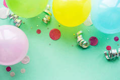 生日快乐或派对背景。平铺在绿色的背景上的生日气球、意大利面和彩带。顶视图。复制空间.
