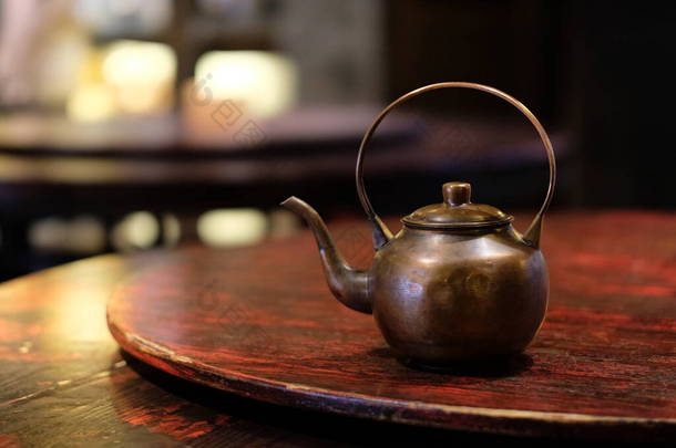把一个旧铜制茶壶关在木制桌子上。传统的中国茶壶。Bokeh background