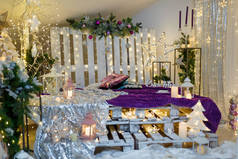 圣诞客厅室内，沙发由托盘、闪亮的星星、花环灯、紫色格子花、冷杉枝条和蜡烛制成。俄语中的幸福. 
