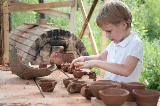 这孩子用粘土做盘子和各种人物形象.陶器技术。业余爱好和兴趣。儿童教育，扩大视野.