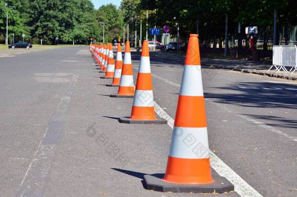 明亮的橙色交通圆锥站在一排沥青路面上
