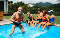 一群快乐的老年人，在后院的室外游泳池，派对的理念.