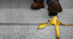 日常生活中的意外概念。男人踩着香蕉皮踩下楼梯。保险或商业隐喻
