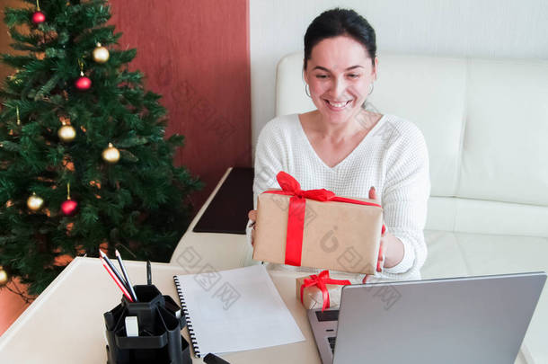 圣诞节网上购物，身穿白色毛衣的年轻女子在礼品盒中展示收到的订单。寒假销售