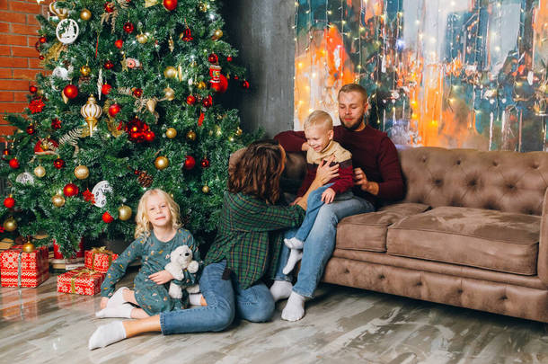 Happy young family with two children at the Christmas tree. Happy new year concept. Toning.