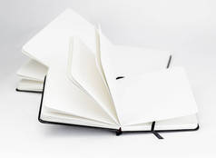 两本黑色的打开的新笔记本，空白的白页和深色的丝带书签在白色的背景上展开
