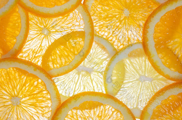橙色和柠檬楔形从下面发出光芒.明亮的柑橘背景。健康的生活方式，维生素，适当的营养，饮食，夏天，新鲜果汁的概念。背景水果质感.