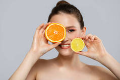 年轻快乐的女人带着美丽的笑容，手里拿着橙子和柠檬片。蓝色背景的