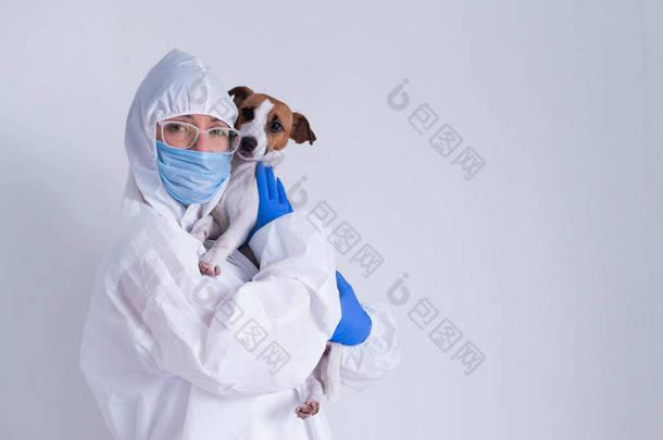 一位身穿防护服、戴着面具的女士，带着一只白色背景的杰克罗素特瑞尔犬