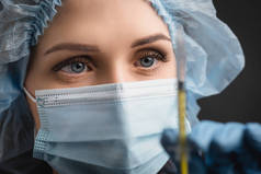 护士长近照，头戴医用面罩，头戴注射器，接种疫苗，前景模糊，深灰色分离