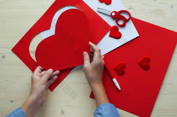  DIY节日卡片,红纸心形,爱情的象征.孩子们做母亲节，情人节，生日贺卡。业余爱好、儿童艺术概念、亲手做礼物、 DIY儿童概念