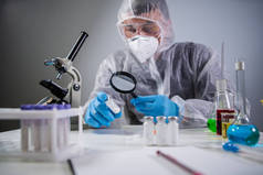 拿放大镜的科学家。在Covid-19和寻找疫苗的过程中，化学家在医学实验室通过放大镜检查了瓶装的考罗那韦疫苗。试验、免疫系统、注射.