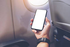 在飞机窗边，一只手拿着一个空白桌面上屏幕的黑色智能手机的模拟图像