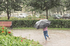 一个小女孩带着雨伞在外面跑来跑去，玩得很开心。雨天.