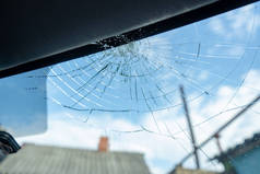 破碎的挡风玻璃，有许多裂缝和小玻璃碎片，损坏的汽车