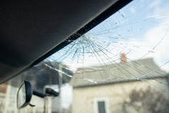 破碎的挡风玻璃，有许多裂缝和小玻璃碎片，损坏的汽车