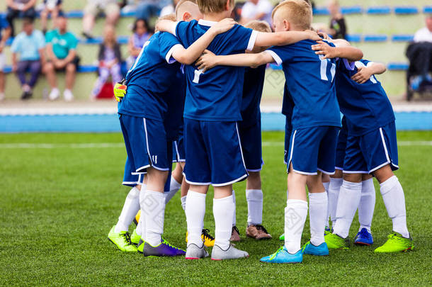 足球队队员成群结队.孩子们在赛前做运动和激励运动。儿童在蓝色足球泽西<strong>运动服</strong>。快乐校园小朋友