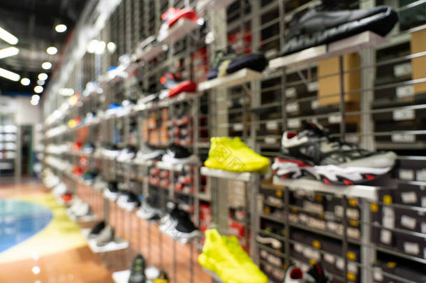 抽象模糊运动鞋在货架上的运动鞋商店背景。许多运动鞋在超级市场的货架上销售，其影响模糊不清.