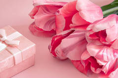 粉红背景的一束粉红郁金香和礼品盒，母亲节或母亲节背景，浪漫贺卡