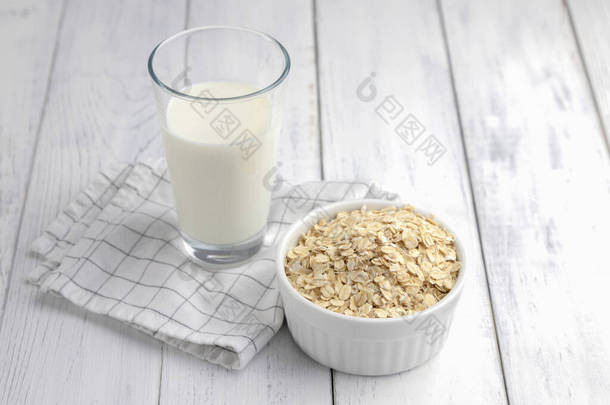 燕麦片、玻璃杯中的蔬菜汁和靠近白色木制背景的燕麦片。特写。素食主义者和素食者的替代牛奶.