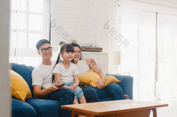 快乐的亚洲家庭享受着在家里共度的闲暇时光。<strong>韩国</strong>人的生活方式<strong>韩国</strong>人的父亲、母亲和女儿一起看电视，在现代住宅客厅的沙发上躺着玩乐.