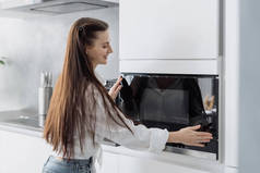 女人们在家里做饭的时候，用新的现代化厨房用具给家人做饭，笑着关上微波炉的电门