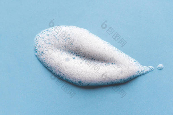 面部清洁慕斯样品。蓝色背景上的白色清洁剂泡沫泡沫.肥皂、淋浴露、洗发水泡沫质感特写.