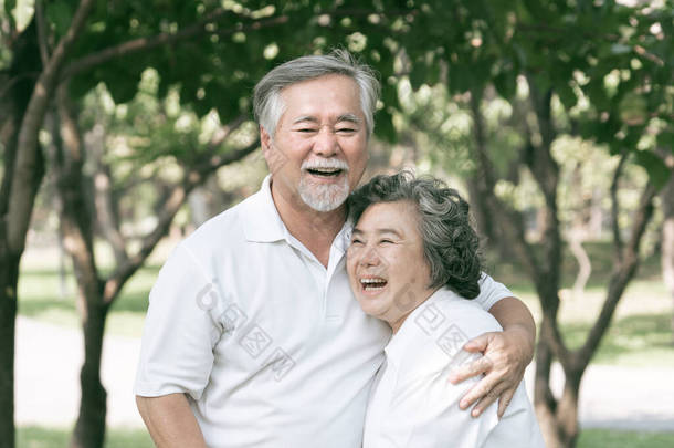 快乐的爱情老年夫妇微笑着面对，老年夫妇老人和老年妇女在森林里放松地拥抱