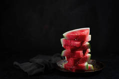 红色生西瓜片，深色背景，有复制空间。它甜甜的，多汁的肉，通常深红色到粉红色，有许多黑色的种子，虽然没有种子的品种存在