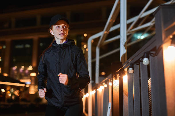 年轻美丽的女运动员在夜市的街上跑来跑去，绕过咖啡店
