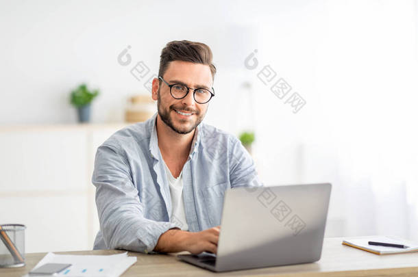 <strong>自由</strong>撰稿人的画像，他坐在写字台前，办公室里带着笔记本电脑，对着相机微笑，<strong>自由</strong>自在的<strong>空间</strong>