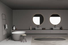深色灰色浴室内部有两个圆形镜子，浮动的水池，一个靠近椭圆形浴缸的凳子和一个地毯。地板设计与大理石搭配.一个简约的概念。3d渲染.