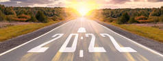 空旷的沥青路面和2022年新年的概念。在通往2022年目标的空旷道路上开车，夕阳西下。2022年写在公路上，箭头在空旷的沥青路面上。2021-2022年远景构想.